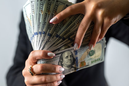 Beautiful young woman in a black jacket with dollar bills on a white background. dollars in female...