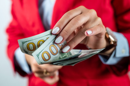 Confident girl pointing to a large amount of dollars in cash in her hands isolated on a white background. paper currency. passive income and wealth. Cashback Deposits. investment. trade.の写真素材