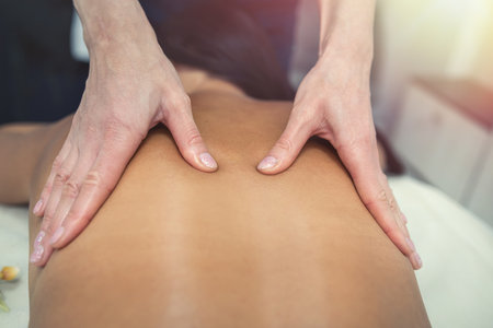 Beautiful young woman lying with closed eyes and enjoy receiving thai massage in a spa salon. beauty and spa conceptの写真素材