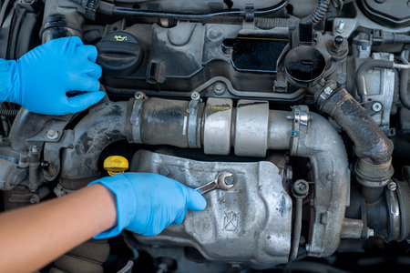 hands of a female mechanic working under the hood of a car in a car service. Empowerment of a woman...