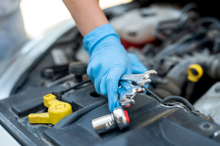 hands of a female mechanic working under the hood of a car in a car service. Empowerment of a woman...