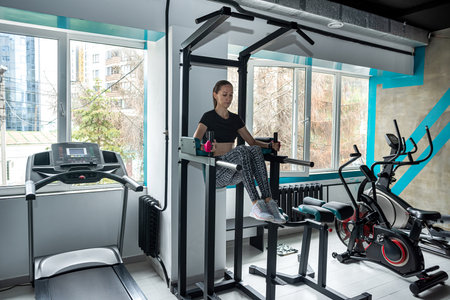 Sporty girl shows her well-trained body in the gym where there are many new exercise machines....