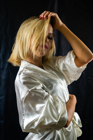 sexy graceful sexy girl in seductive pajamas posing on a plain dark background. isolated studio portrait of a girlの写真素材