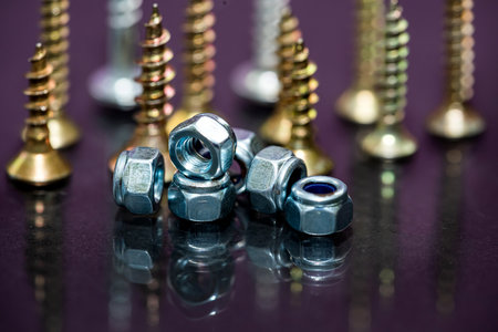 row of coated screws or self-tapping screws on a black mirror background. repair concept.