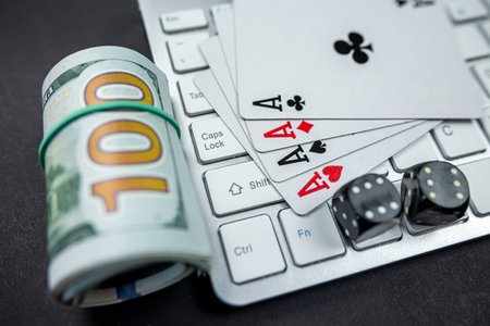 dollar bills and casino dice and cards on laptop keyboard isolated on black background. Gambling....