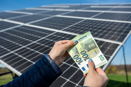 Human hands with euro fan in front of solar panels. The concept of energy conservation. green...