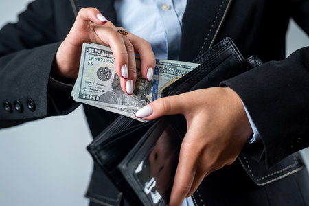 close-up of a female hand holding a black wallet in which there are dollars. woman with dollars...