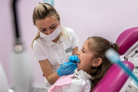 beautiful little female patient grimaces during an examination of the oral cavity by a female dentist. toothache in children. oral healthの写真素材