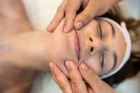 girl client is lying down for a facial massage in the best spa salon in town. close up face massage satisfied customerの写真素材