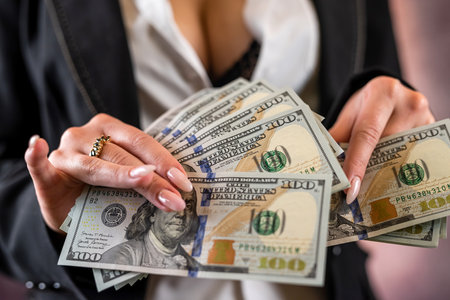 beautiful young girl holds a fan of dollar bills in her hands. isolated on plain background. profit and prosperity.の写真素材
