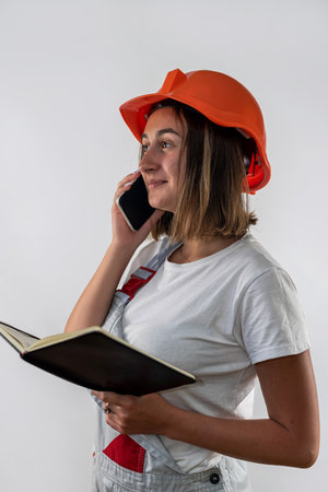 beautiful female construction worker holding a folder with documents in her hands and smiling. Isolated on a plain background. portrait of a woman. repair in the apartmentの写真素材