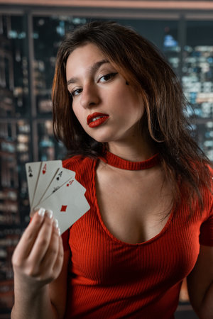 Beautiful Caucasian woman in red dress with poker cards gambling in casino posing and smiling. poker...