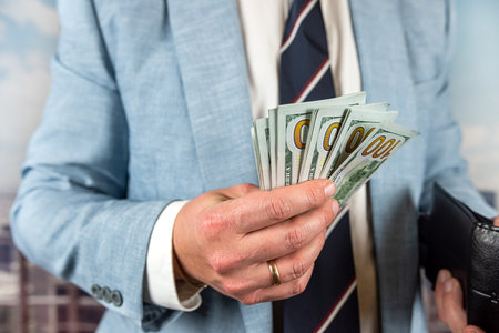 successful male agent in suit holding US dollar bills. money and finance concept