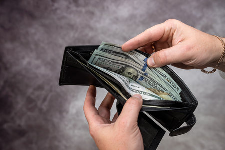 closeup businessman hand holding money dollar in black wallet purse. bribe concept. exchange moneyの写真素材