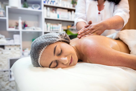 masseuse massages the back of a female client on a massage table close-up. spa salon concept. healthy bodyの写真素材