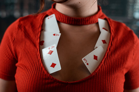 beautiful girl in a red dress with a neckline in which poker cards. woman in poker games of chance...