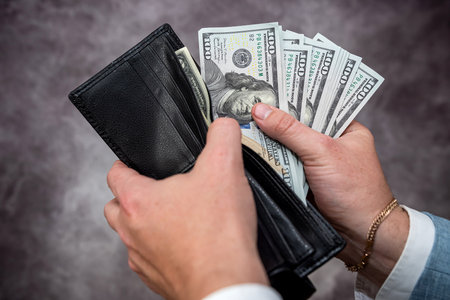 Businessman hands holding black leather wallet with dollar bills. financial conceptの写真素材