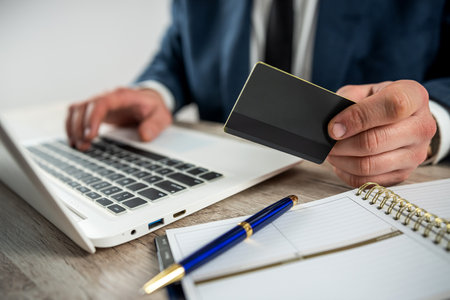 Man in suit shopping online and pay by credit card using laptop at home or officeの写真素材
