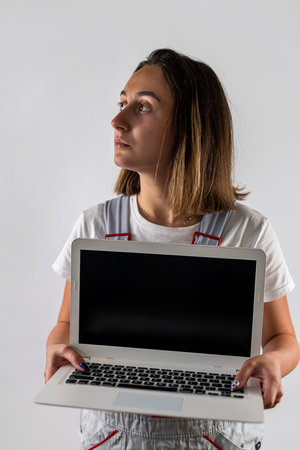 female construction worker holds a laptop in her hands. isolated on a white background. portrait. woman in uniform. portrait of a womanの写真素材