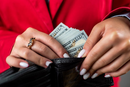 young beautiful woman with fragile hands takes out many dollars from her purse. business woman. a lot of people money in walletの写真素材