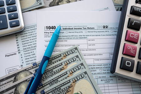 us dollar cash pen and calculator over blank 1040 tax form. annual report, paper workの写真素材