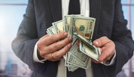 closeup male agent in suit hold dollar bills in hand to pay expenses or shopping, finance conceptの写真素材