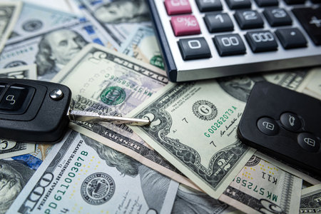 Calculator with two black real car keys over American dollars as background. Leasing or purchase for autoの写真素材
