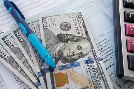 2022 blank 1040 individual tax form with dollar money calculator nad pen on office desk. Paperwork, accounting document. Deadline, tax timeの写真素材
