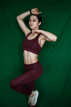 Portrait of young caucasian woman in sports outfit isolated on green. lifestyle