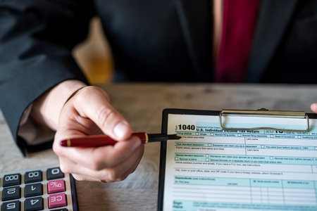 cropped photo of business man in jacket filling out tax forms and making calculations at desk....