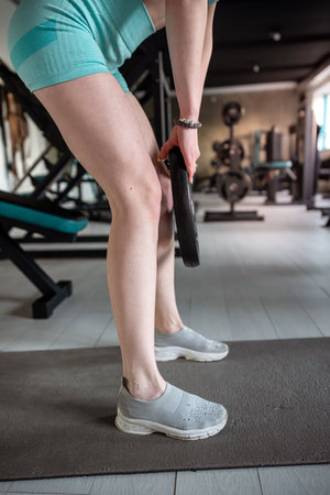 Strong red hair woman doing exercise with weight plate in the gym. Functional training, lifestyleの写真素材