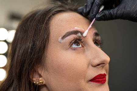 an eyebrow artist is laminating the eyebrows of a beautiful client. eyebrows