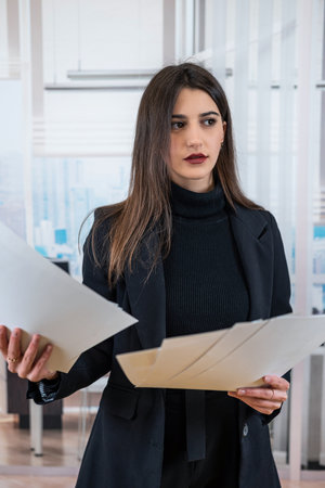 Single happy confident caucasian female manager in suit holding documents posing at office. Successful businesswomanの写真素材