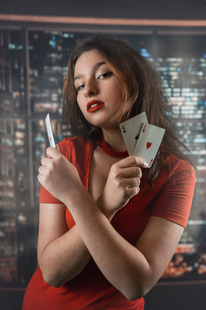 Beautiful Caucasian woman in red dress with poker cards gambling in casino posing and smiling. poker...