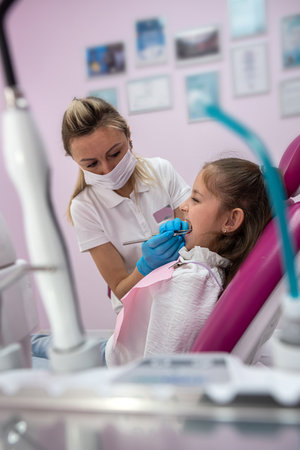 beautiful little female patient grimaces during an examination of the oral cavity by a female dentist. toothache in children. oral healthの写真素材