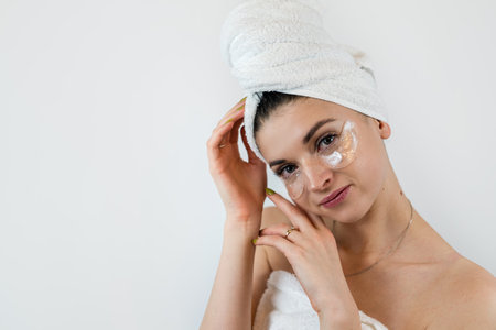 Charming female lady using collagen patch under eye for clean smoothing skin isolated on white....