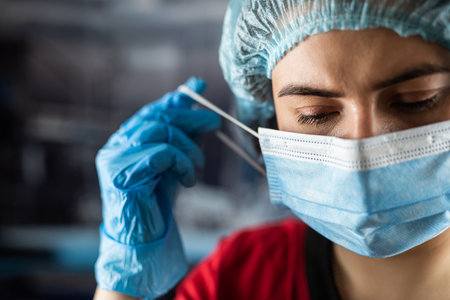 Portrait of tired young doctor taking off medical face mask after a shift in clinic. Healthcare...