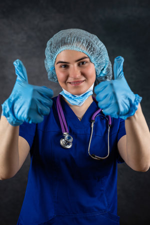 Young female doctor wear uniform shows thumb up in approval, healthcare workers. Overcoming disease illnessの写真素材