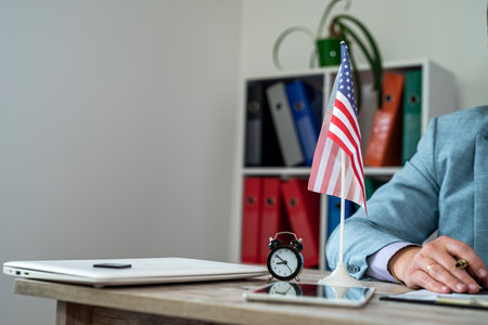 hands of a man in a suit behind a table with an American flag on it. business business styleの写真素材