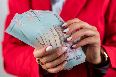 young fragile hands of a woman hold a fan with thousands of hryvnias. money of Ukraine. a wealthy woman hryvnias in handsの写真素材