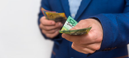 man wearing blue business suit hold australian dollars bills isolated grey background. Finance conceptの写真素材