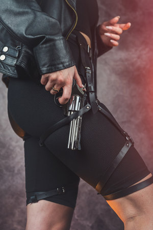 slim woman wearing leather black jacket clothes with handgun isolatedの写真素材