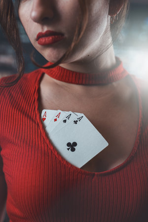 beautiful girl in a red dress with a neckline in which poker cards. woman in poker games of chance excitementの写真素材