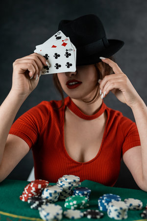 poker player sits at a poker table with cards in her hands and poker chips on the table. poker. casinoの写真素材