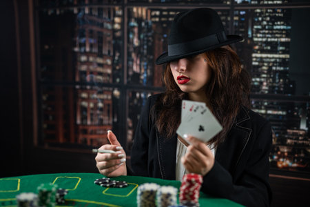 woman's hand takes poker cards at a round poker table. risky bets in poker. casino. a woman in a hatの写真素材