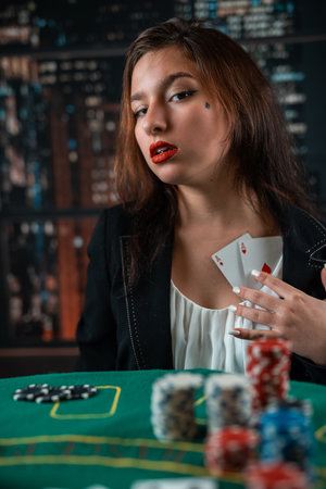Female hand with playing cards and poker chips close-up in front of poker table. poker concept. game for money cunning woman in the casinoの写真素材