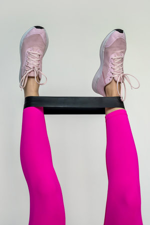 Legs of a girl with an elastic band made of beautiful colored fabric during training isolated on a white background. sports theme. Healthy Lifestyleの写真素材