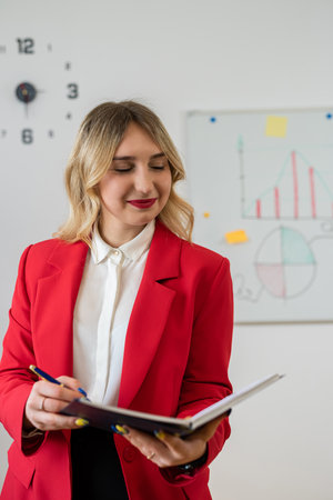 Female manager in red suit making presentation with office board flip chart with business graph chart or finance report.の写真素材