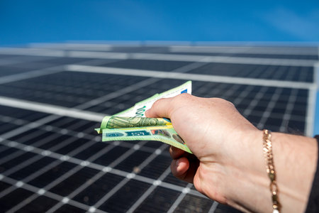 strong male hands of a worker holding euro banknotes for work done. The concept of paying for the installation of solar panels. green electricityの写真素材