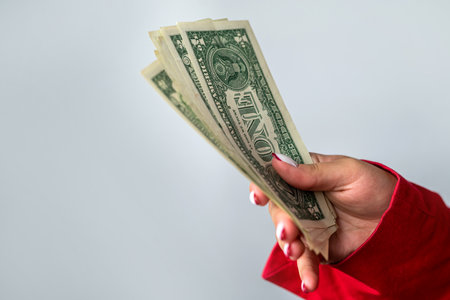 Beautiful young woman in a red jacket holding a pile of money isolated on a white background. business woman. a lot of money in handの写真素材